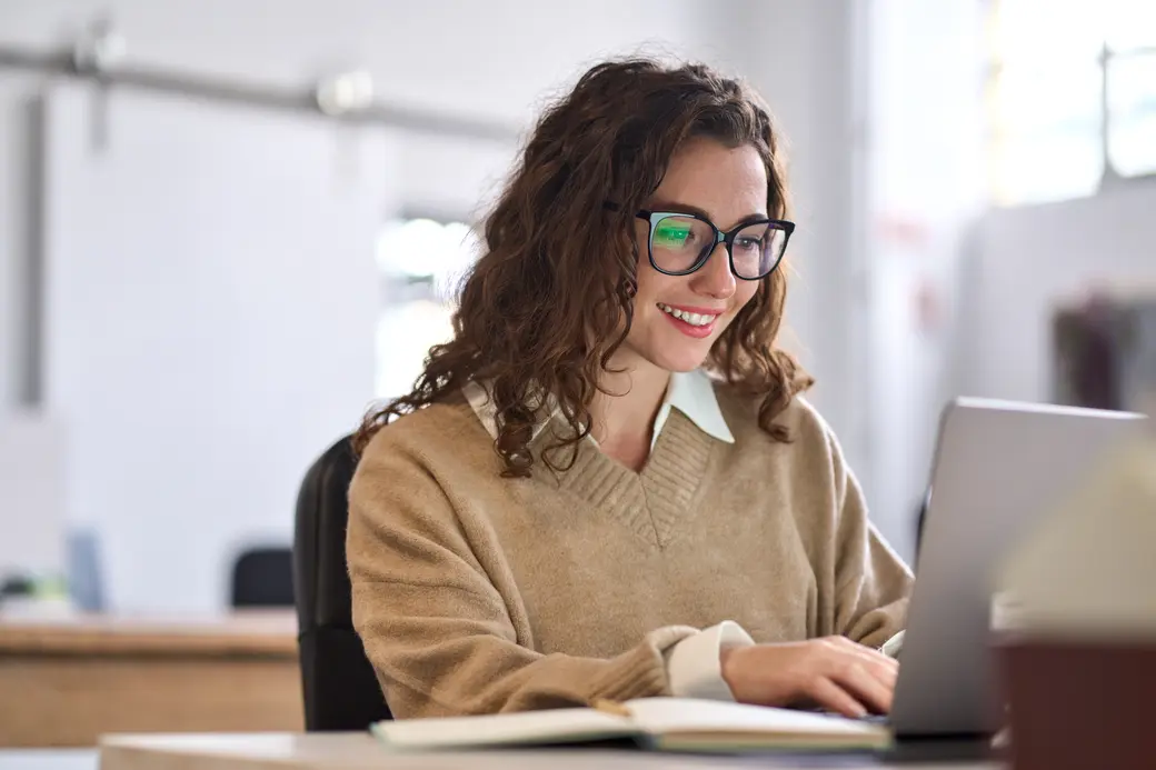 Studentin sitzt am Schreibtisch mit Laptop