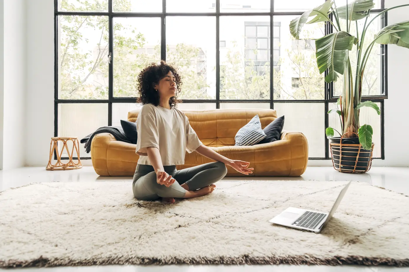 Frau, die zu Hause an Online-Video-Meditationsunterricht mit Laptop teilnimmt.