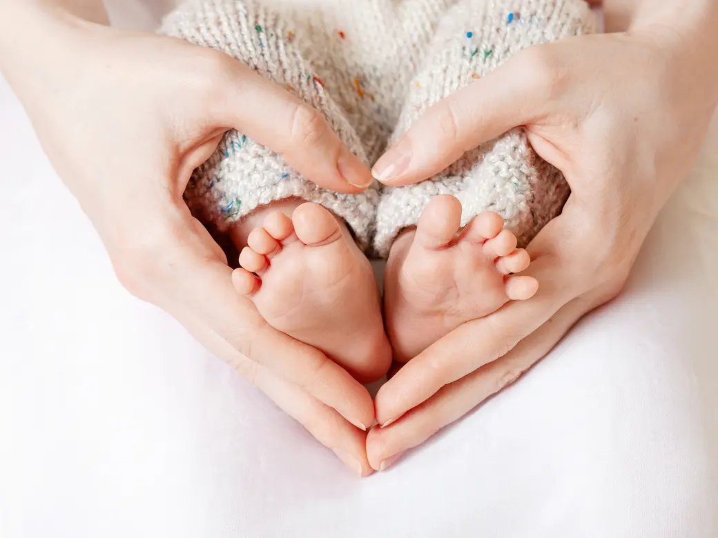 Babyfüße in Mutterhänden
