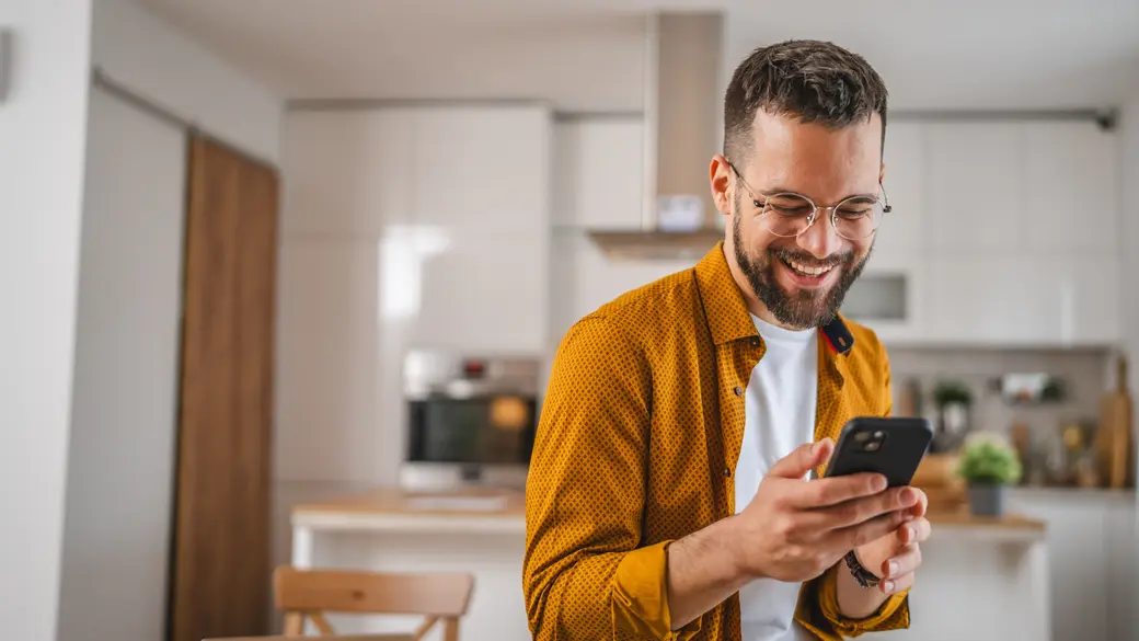 Mann mit Brille nutzt sein Handy zu Hause in der Küche