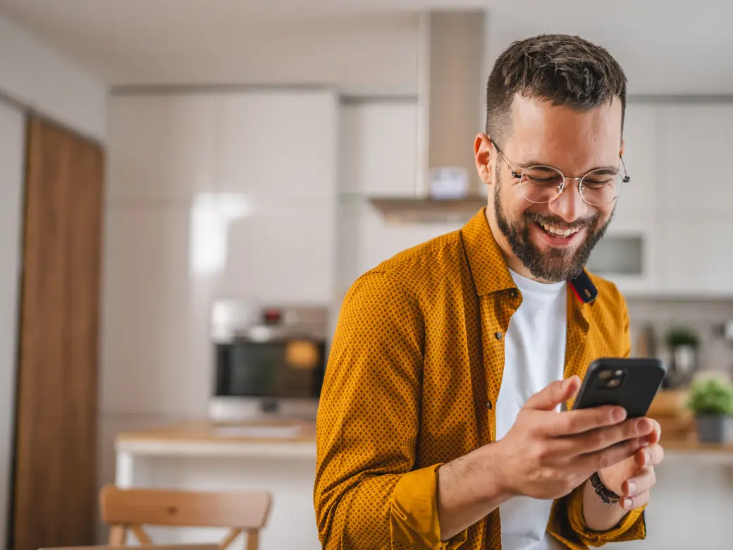 Mann mit Brille nutzt sein Handy zu Hause in der Küche