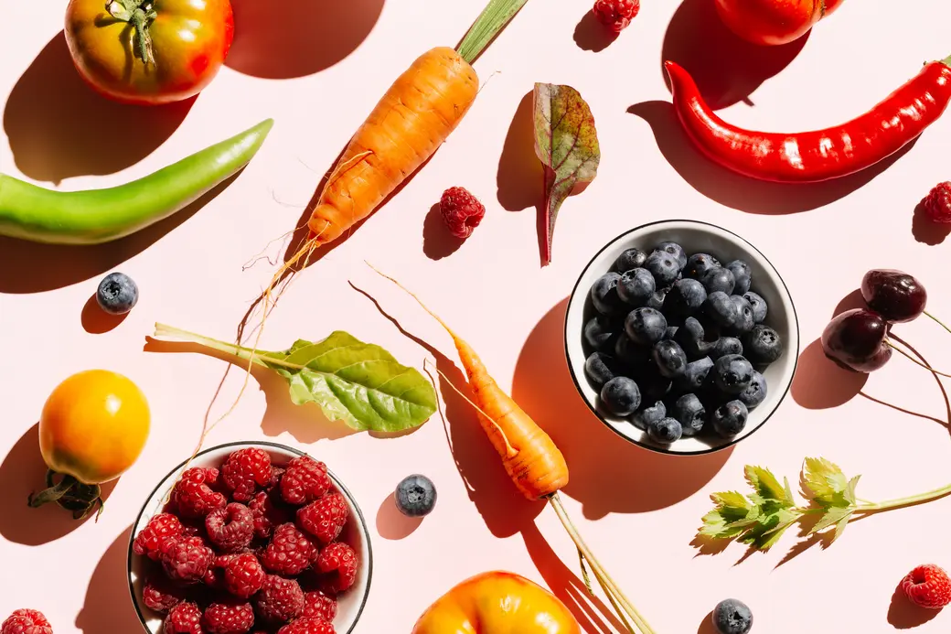 Flatlay aus Obst und Gemüse auf rosa Hintergrund