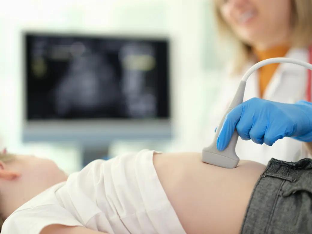 Arzt führt abdominale Ultraschalluntersuchung der inneren Organe des Kindes durch