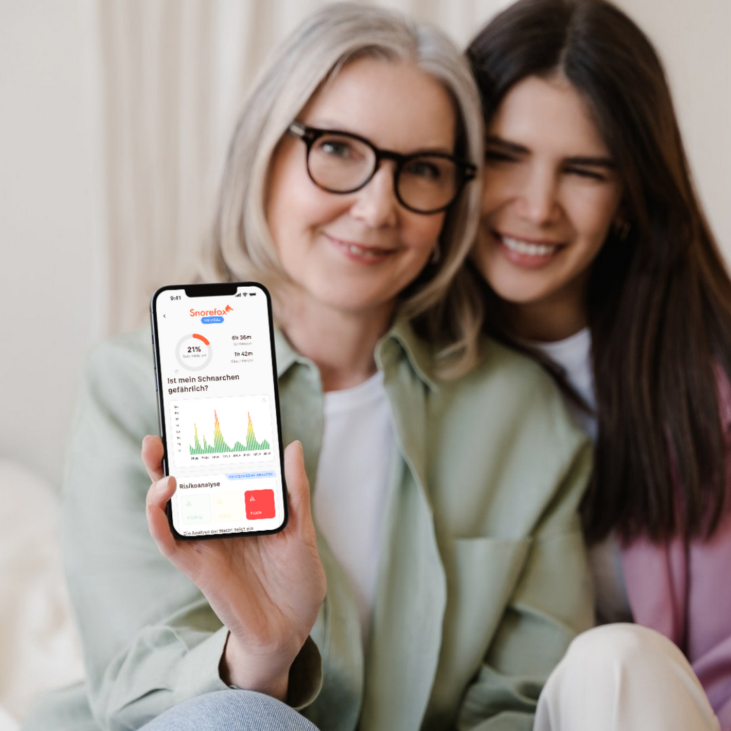 Zwei Frauen zeigen das Handy mit der Snorefox-App in die Kamera